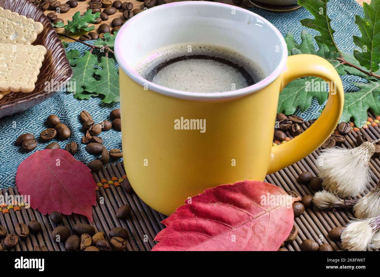 Tasse warmer Kaffee auf dem mit Herbstblättern verzierten Tisch Stockfoto