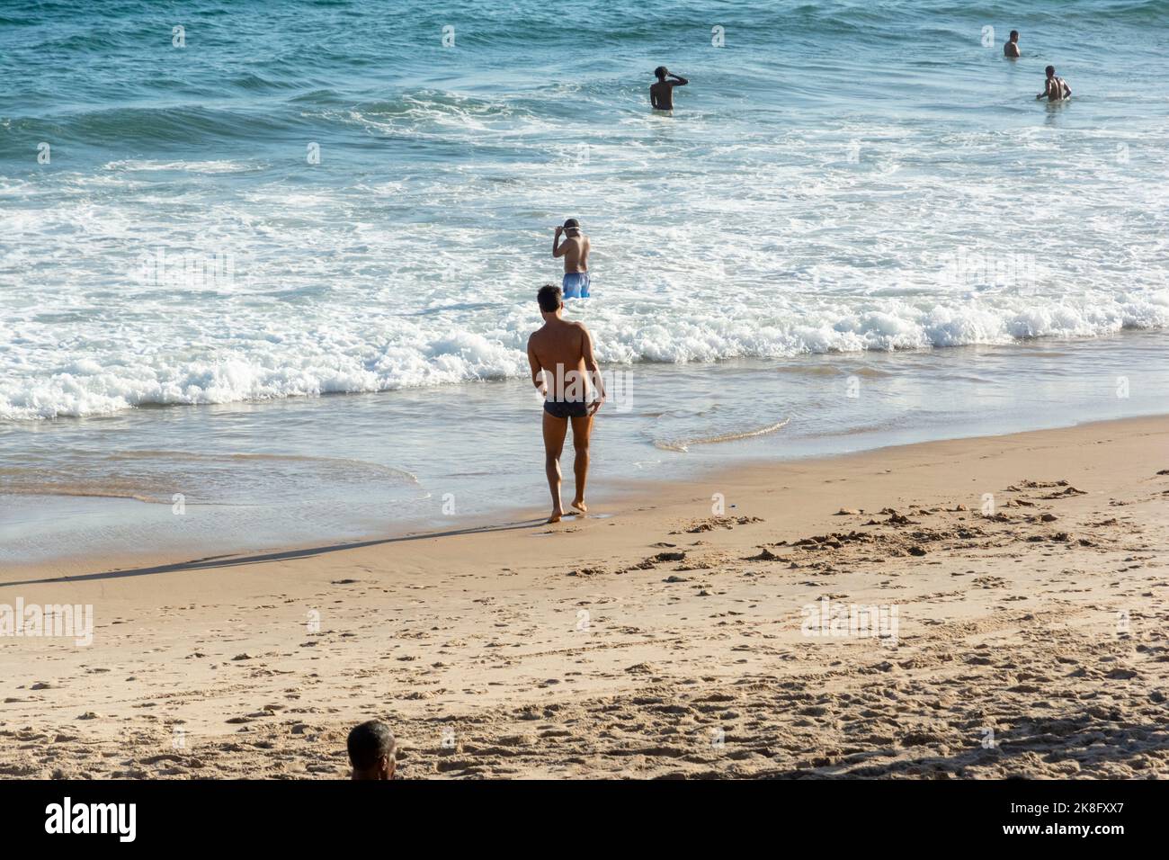Salvador, Bahia, Brasilien - 22. Oktober 2022: Menschen, die am Samstagstag im Frühling am Strand Farol da Barra in Salvador, Brasilien, ins Wasser kommen. Stockfoto
