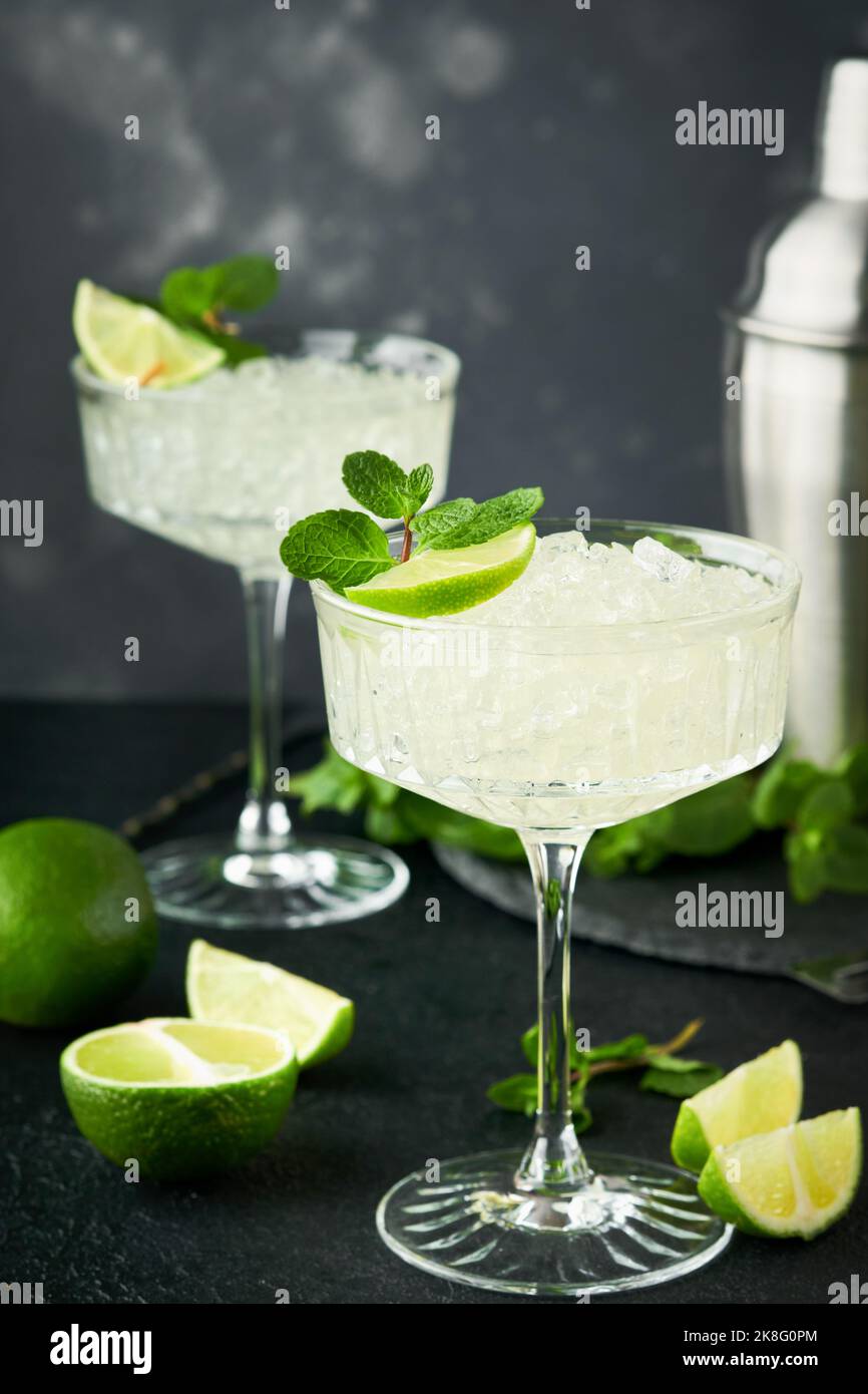 Margarita Cocktail mit Limette, Tequila, Minze und Eis auf dunklem Tisch mit erstaunlicher Hintergrundbeleuchtung, Kopierraum. Klassischer Margarita- oder Daiquiry-Cocktail. Barkarte Stockfoto