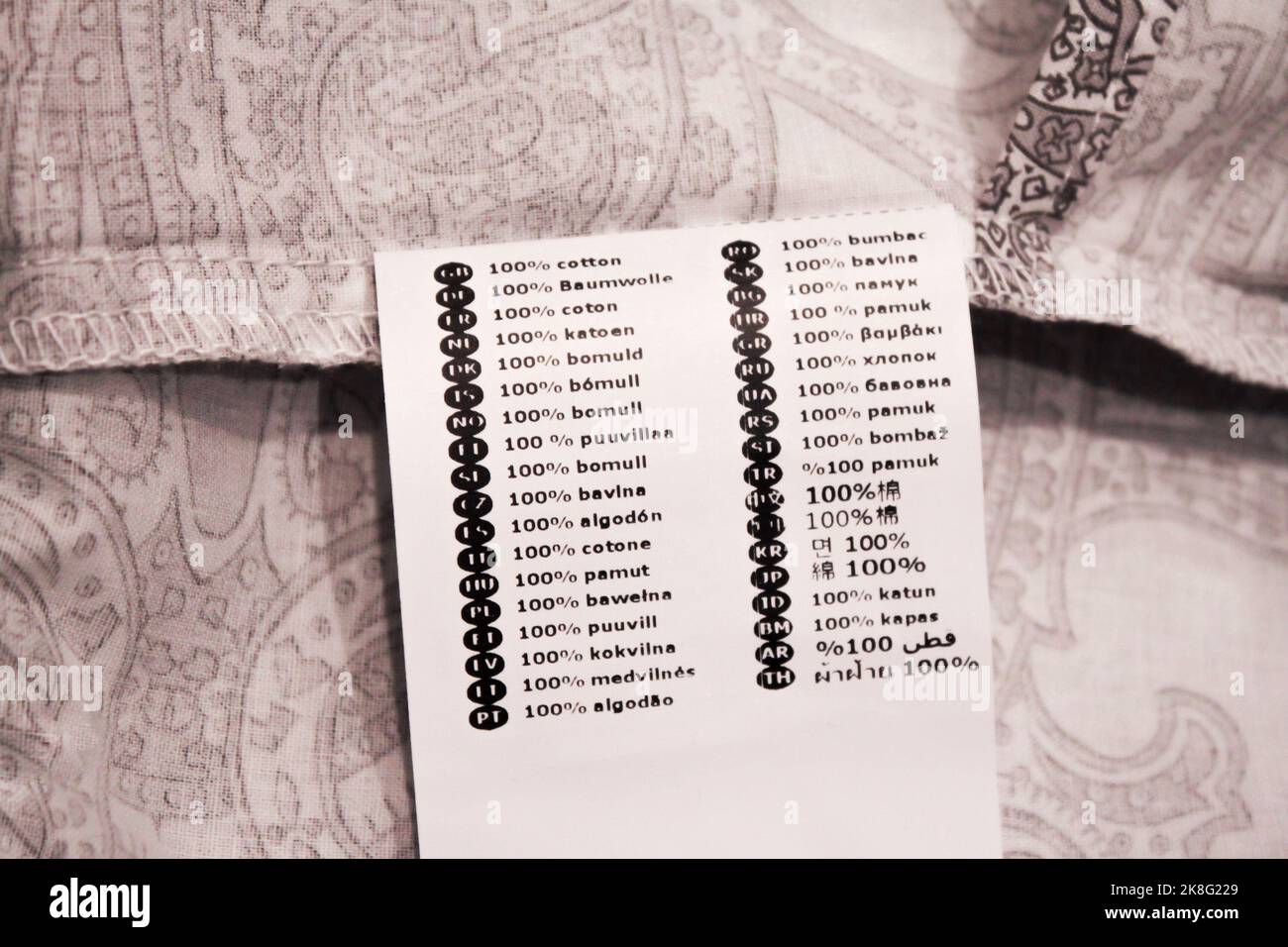 Weiße Wäscheetikette mit Schild Baumwolle in 36 Sprachen auf Bettwäsche. Stockfoto