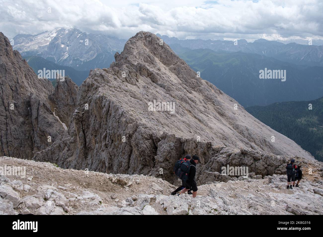 Verschiedene Bergsteiger in den italienischen Dolomiten beim Abstieg vom Plattkofel-Gipfel mit dem Marmolata-Berg im Hintergrund. Stockfoto