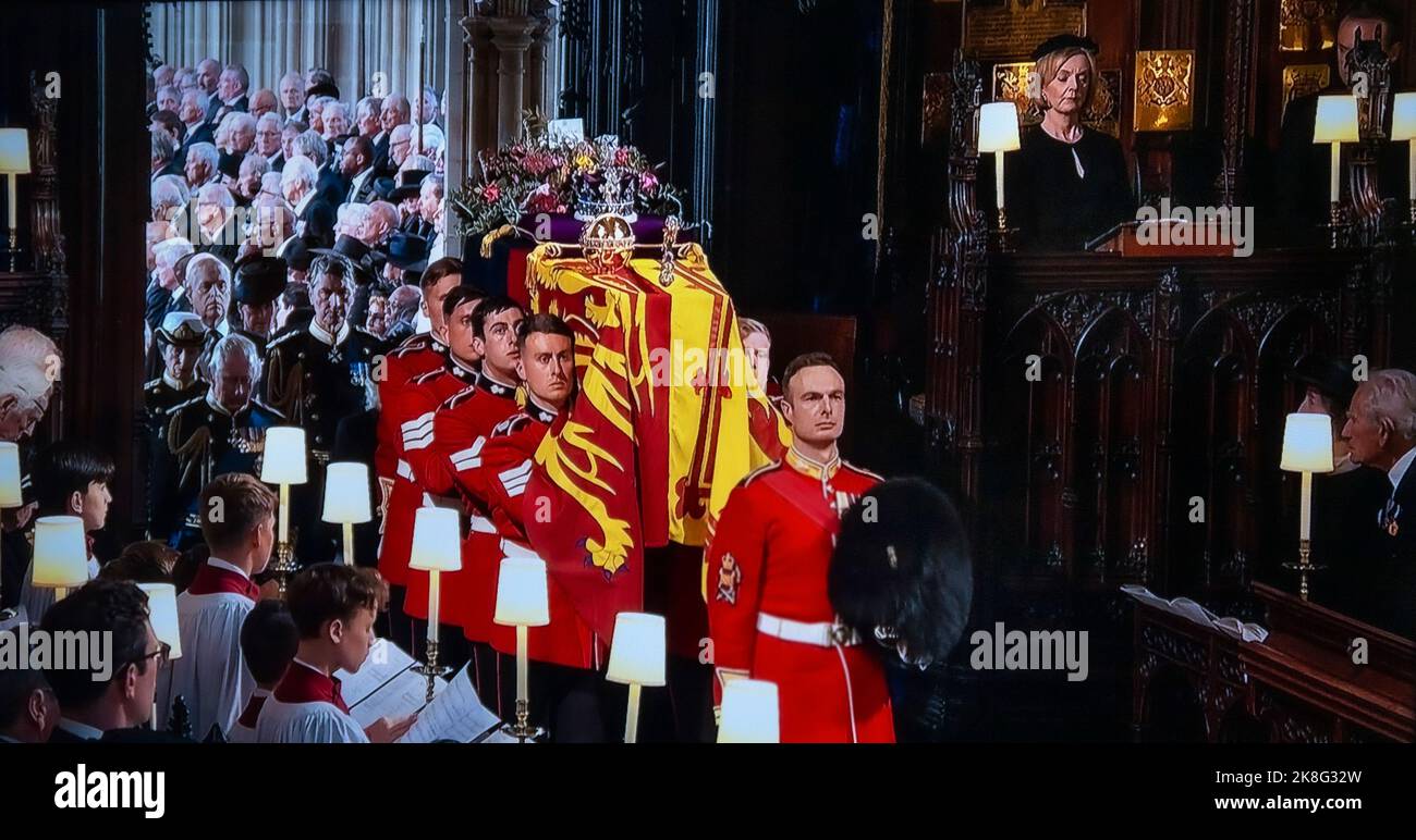 BEERDIGUNG Königin Elizabeth II Beerdigungsträgerpartei Tragen Sie den Sarg Ihrer Majestät in das Innere der St. George's Chapel mit der Standardflagge des Souveränen, der Krone des Kaiserlichen Staates, der Kugel und dem Zepter auf der Oberseite. Die (damalige) britische Premierministerin Liz Truss ist oben rechts in einem privaten Stall zu sehen. 19.. September 2022 Windsor Castle 9. September 2022 – das Staatsfuneral Ihre Majestät Königin Elizabeth II Stockfoto