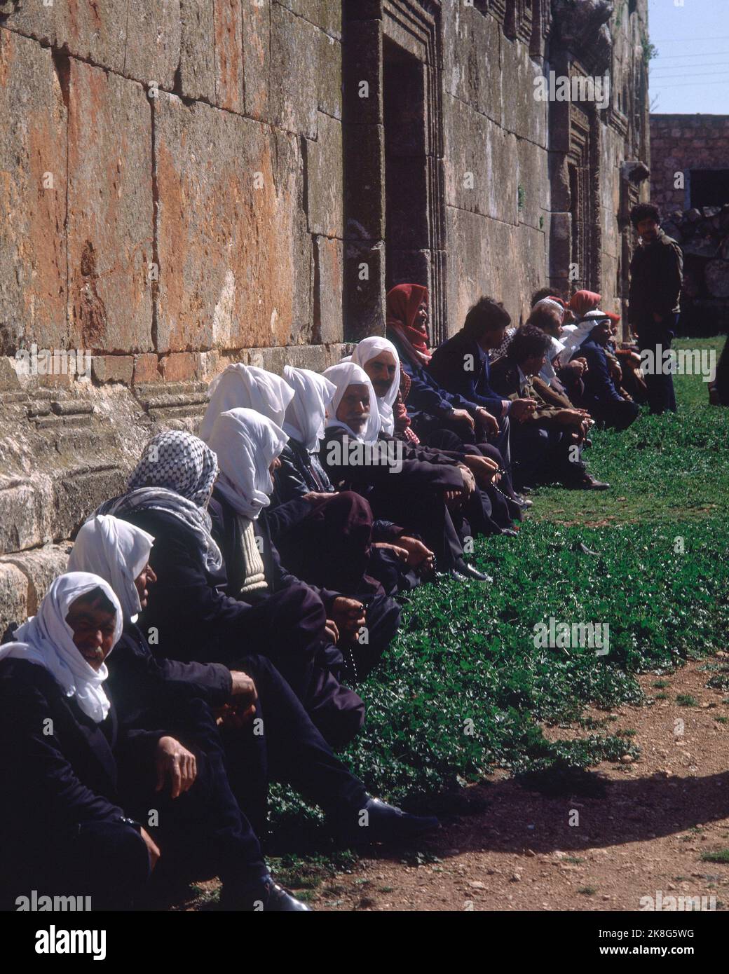 ARABES SENTANDOS EN EL EXTERIOR DE LA BASILICA CONSTRUIDA EN EL SIGLO V. LAGE: BASILIKA. QALBLOZE. Stockfoto