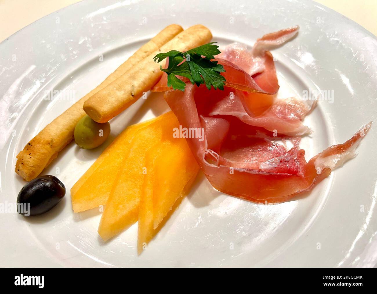 Ein serviertes Gericht aus Jamon Serrano mit Scheiben Wassermelone, Oliven und Brotscheiben Stockfoto