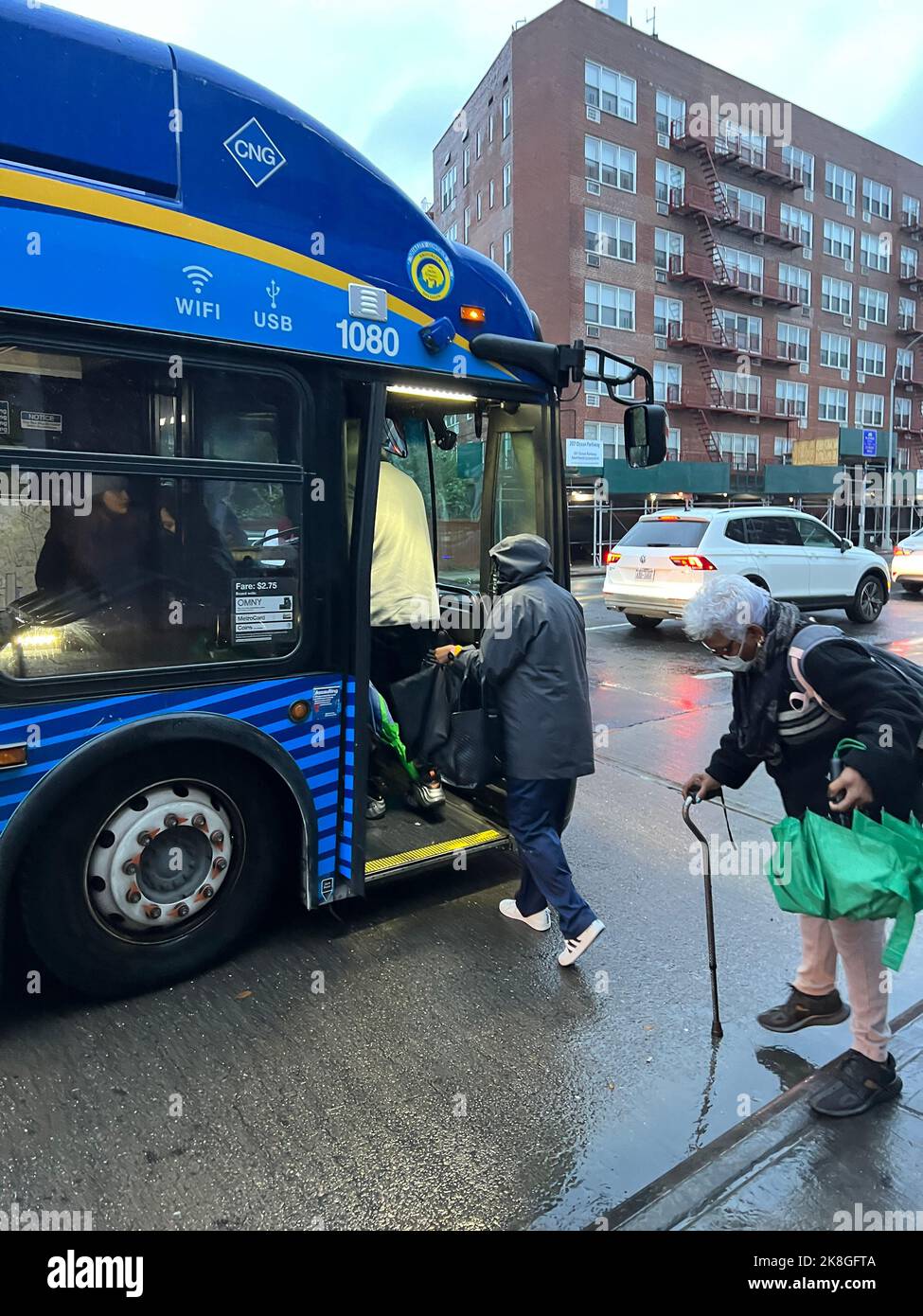 Ältere Menschen boparden vorsichtig einen Stadtbus an einem rauschigen, rutschigen Tag in Brooklyn, New York. Stockfoto