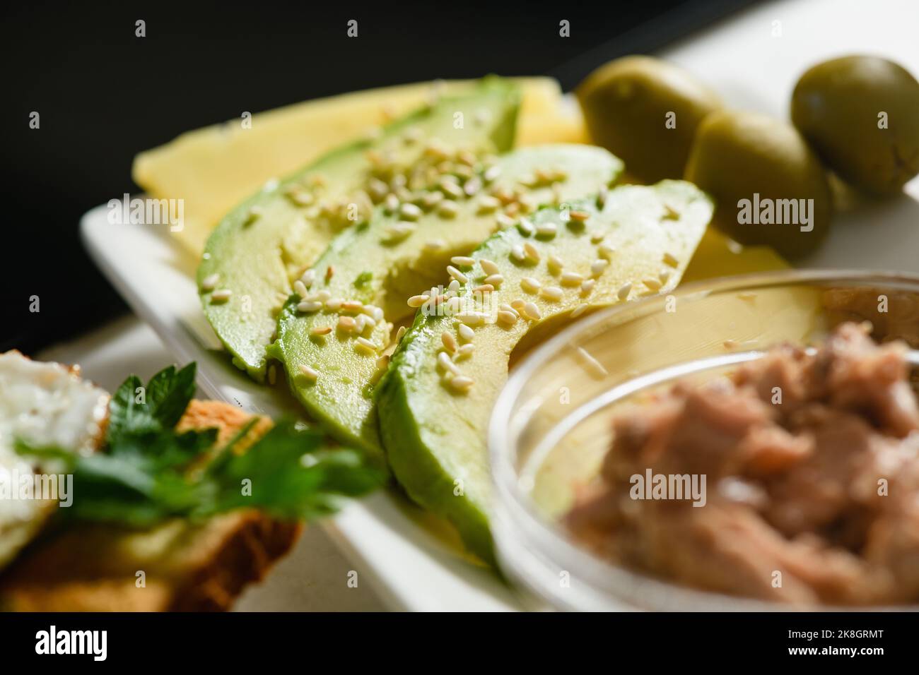 Appetitliche Avocado-Scheiben mit Sesam auf Käse. Frühstück am Morgen. Nahaufnahme. Stockfoto