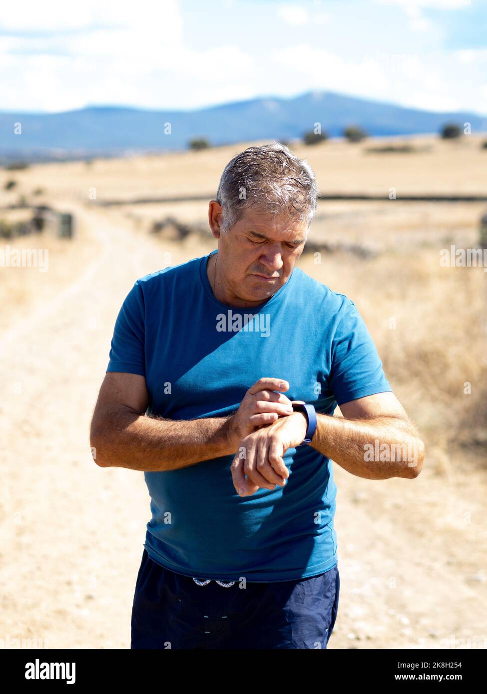 Spanischer älterer Mann, der eine Sportuhr beim Sport ansieht. Läufersport-App Stockfoto