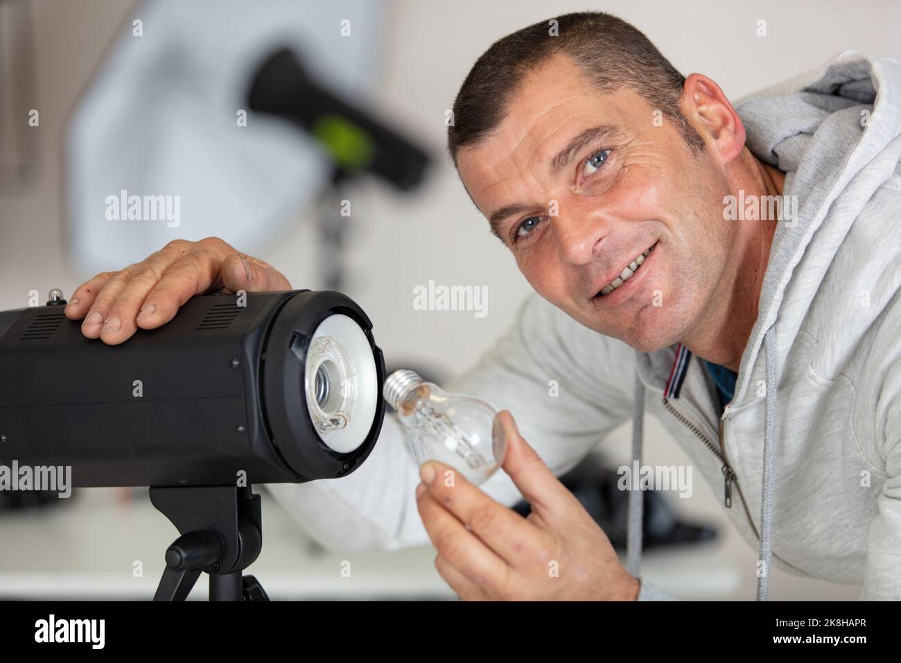 Junger Mann ändert die Blitzeinstellungen im Studio Stockfoto