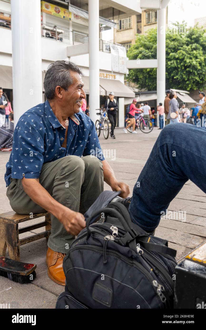 Schuhe in einem Waschbecken mit Seifenwasser. Reinigung der Schuhe auf der Straße, lateinischer alter Mann, Stockfoto