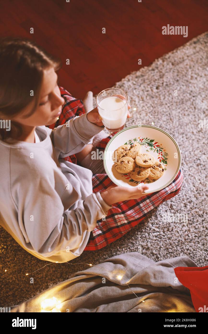 Netter Junge bereit für den Weihnachtsmann wartet mit Keksen und Milch. Der Glaube an das Märchen Stockfoto