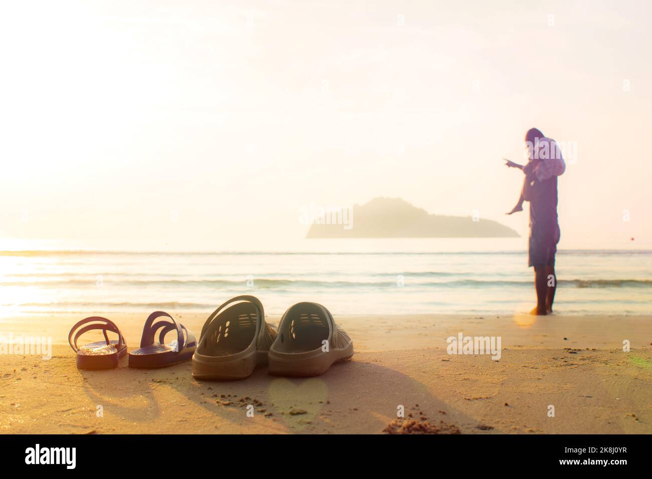 Vater und Tochter ziehen ihre Sandalen aus und liegen am Strand. Tochter reitet Vater den Hals für einen Morgenspaziergang. Stockfoto
