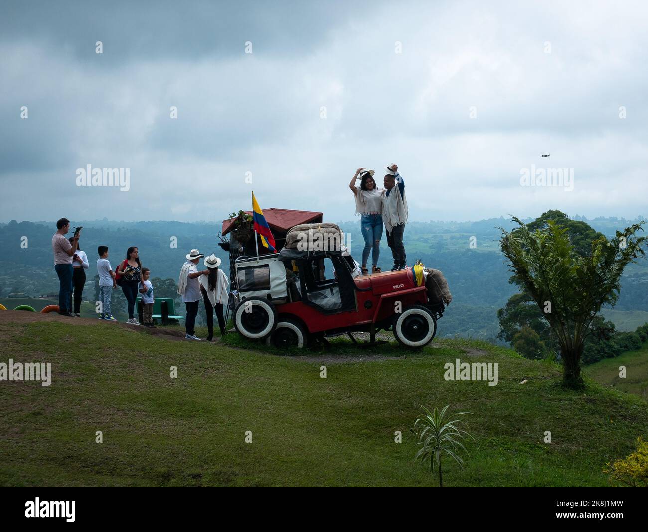 Filandia, Quindio, Kolumbien - 5 2022. Juni: Touristen stehen auf einem roten Jeep in typisch kolumbianischer Kleidung, während andere Leute auf ihren Turn warten Stockfoto