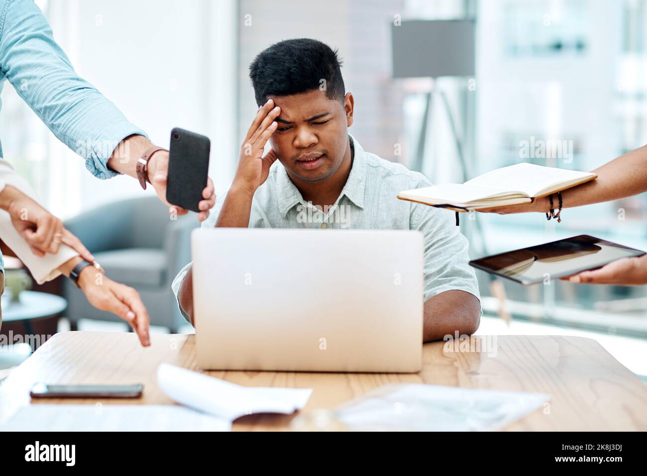 Bei der Arbeit überfordert zu sein kann Ihre Produktivität und Ihre Gesundheit schädigen. Ein junger Geschäftsmann, der gestresst in einem anspruchsvollen Büroumfeld aussieht. Stockfoto