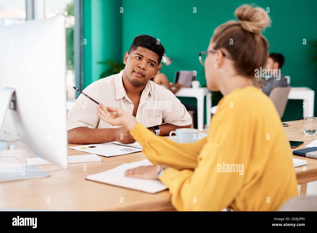 Gemeinsame Arbeit an einer bevorstehenden Kampagne. Zwei junge Designer arbeiten gemeinsam an einem Computer in einem Büro. Stockfoto