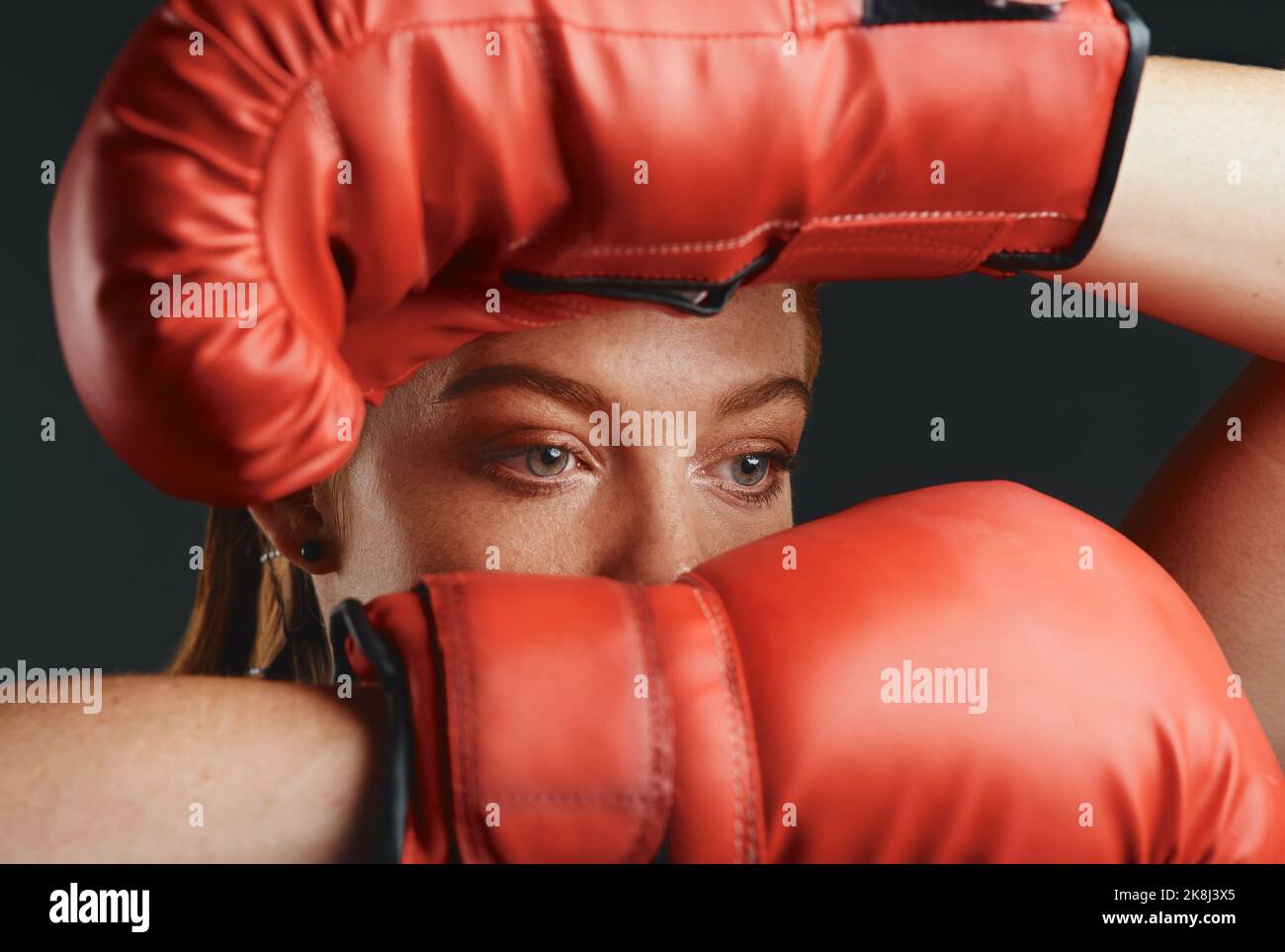 Das Feuer in mir brennt heller als das Feuer um mich herum. Studioaufnahme einer sportlichen jungen Frau, die Boxhandschuhe vor schwarzem Hintergrund trägt. Stockfoto