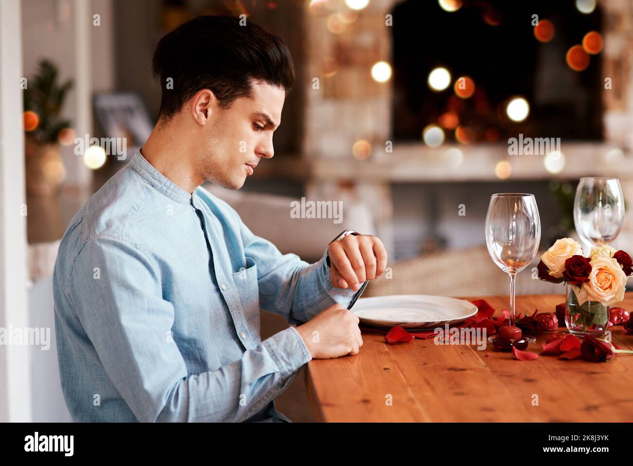 Ich gebe ihm weitere 10 Minuten. Ein Mann, der die Zeit überprüft, während er an einem Esstisch auf sein Date wartet. Stockfoto