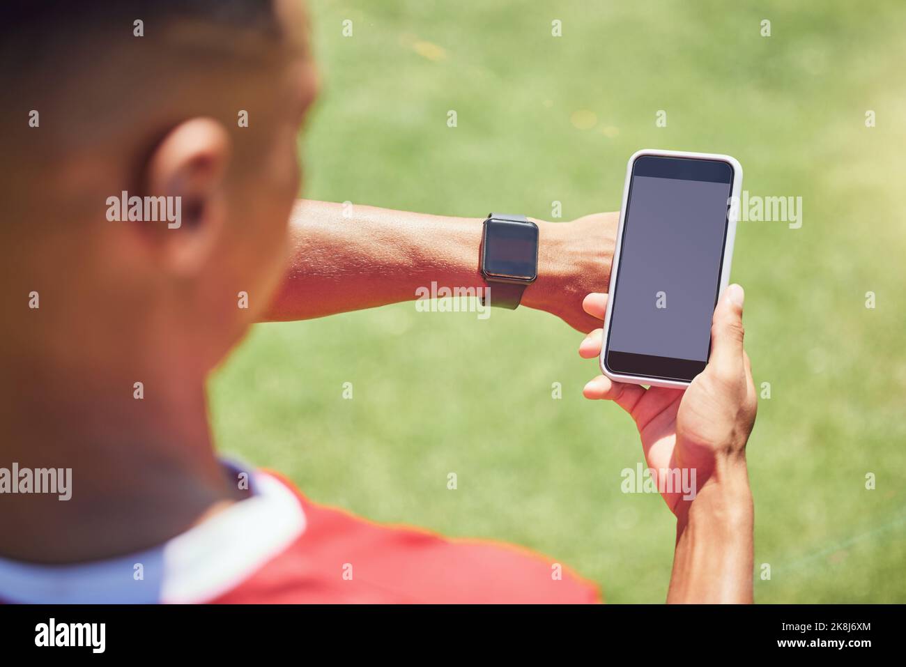 Grüner Bildschirm, Fußballspieler und Telefon auf dem Spielfeld mit Smartwatch, Tech oder Mockup auf der mobilen digitalen App. Mann, Fußballspieler oder Smartphone auf Social Media Stockfoto