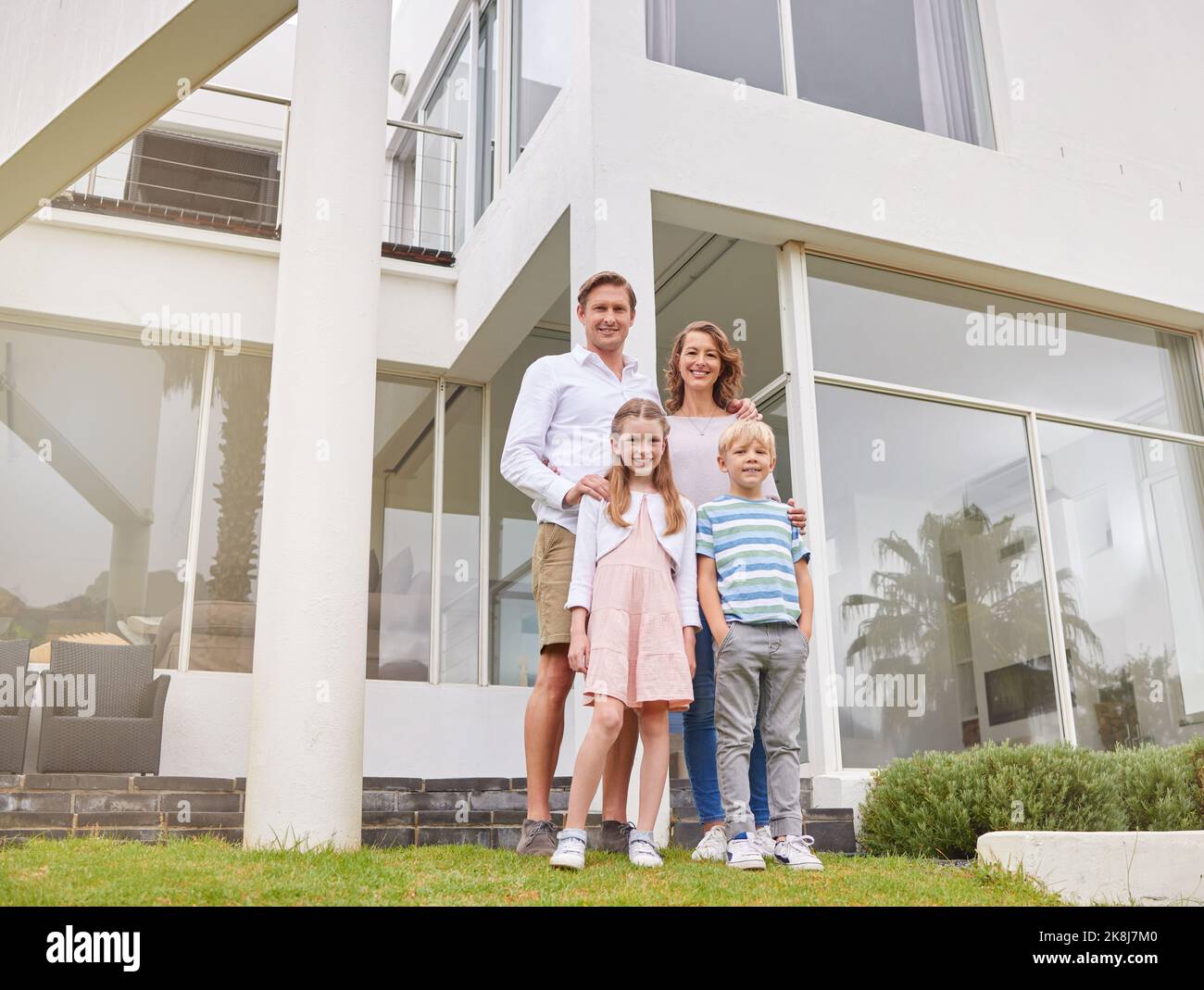 Mutter, Vater und Kinder in einem Immobilienhaus für ein glückliches Familienportrait und einen wohlhabenden Lebensstil im Freien. Mama, Papa und Kinder zusammen Stockfoto