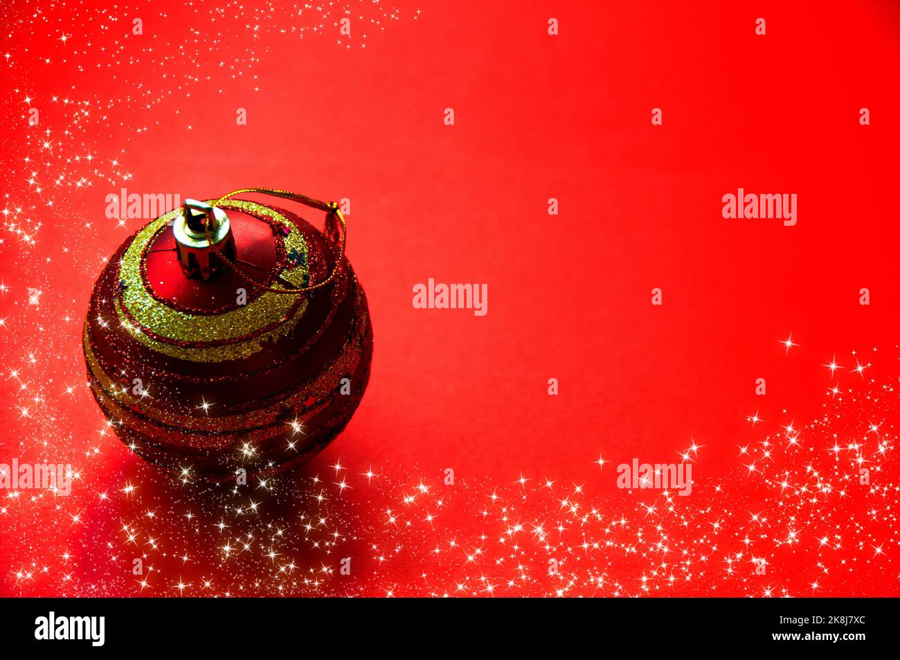 Weihnachtskugel mit leuchtenden Sternen auf rotem Hintergrund. Anpassbarer Platz für Text und Ideen. Speicherplatz kopieren. Stockfoto