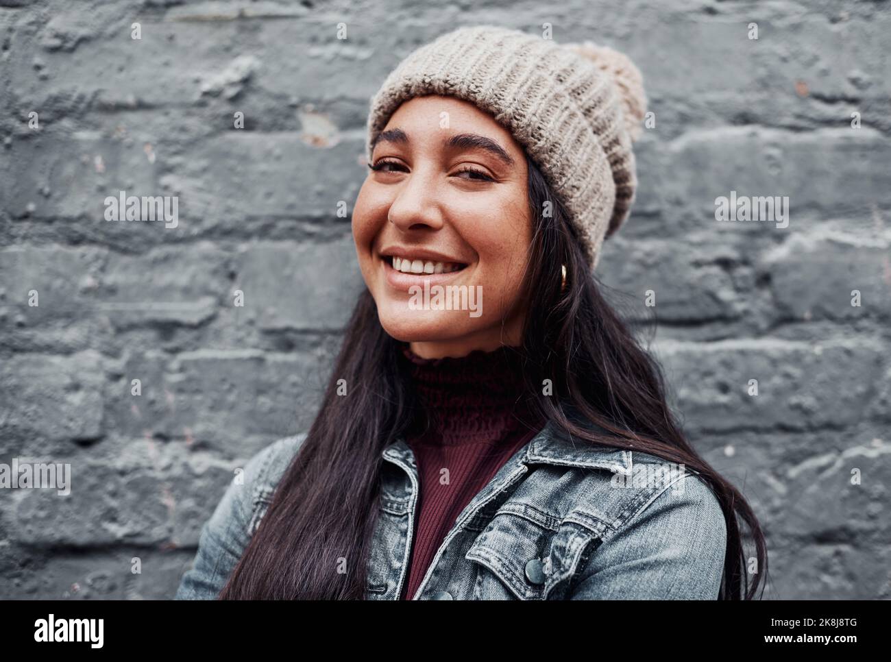 Glück ist es, was einen schön macht. Beschnittenes Porträt eines attraktiven Teenagers, das allein gegen eine graue Wand in der Stadt steht. Stockfoto