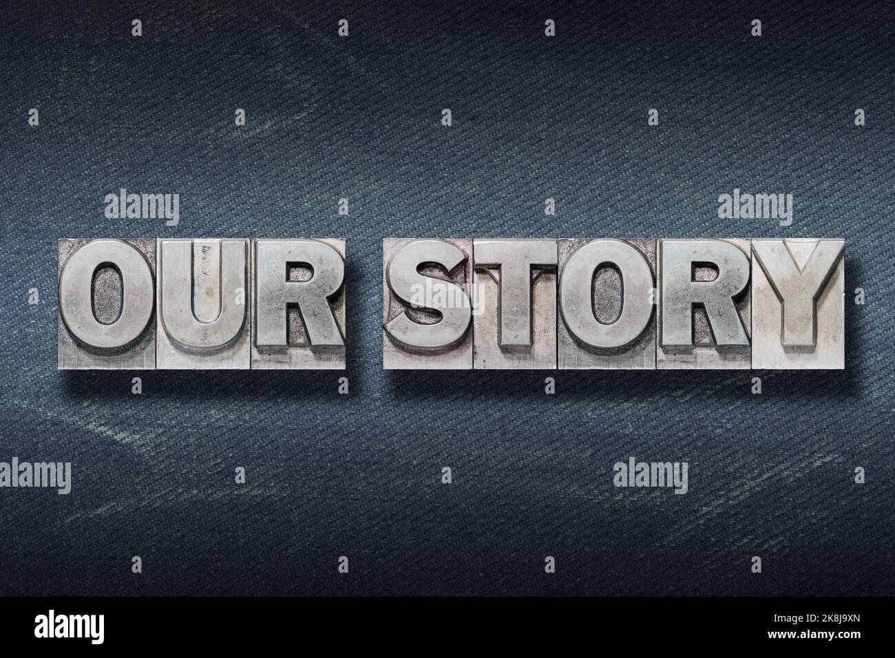 Unser Storyphrase aus Metallic-Buchdruck auf dunklem Jeans-Hintergrund Stockfoto