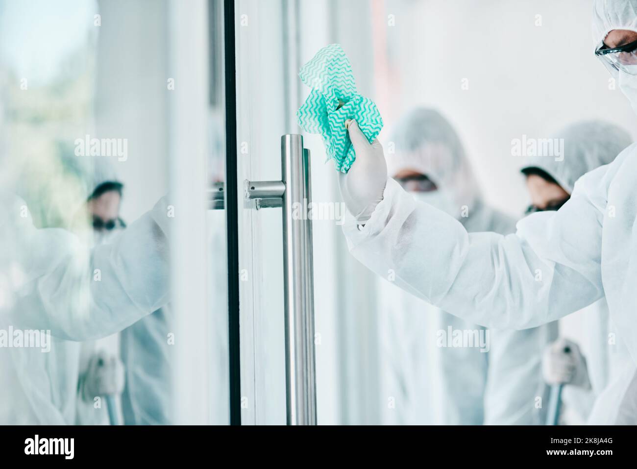 Nur weil es unsichtbar ist, heißt es nicht, dass es nicht da ist. Mitarbeiter im Gesundheitswesen tragen Hazmat-Anzüge und desinfizieren einen Raum während eines Ausbruchs. Stockfoto