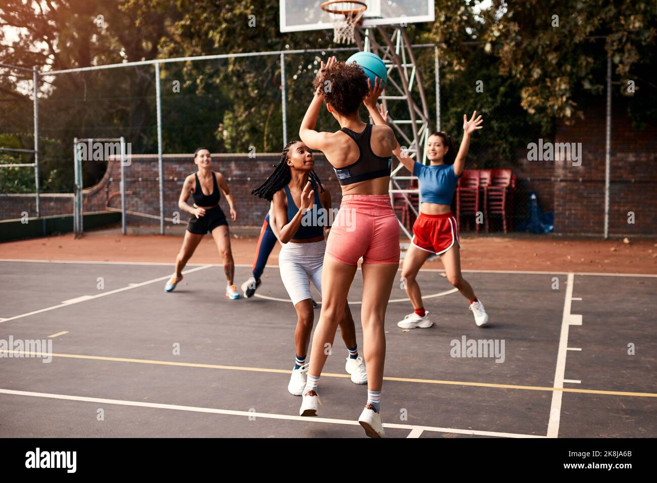 Ich arbeite hart für meinen Schuss. Eine vielfältige Gruppe von Sportlerinnen spielt tagsüber gemeinsam ein Wettkampfspiel mit Basketball. Stockfoto