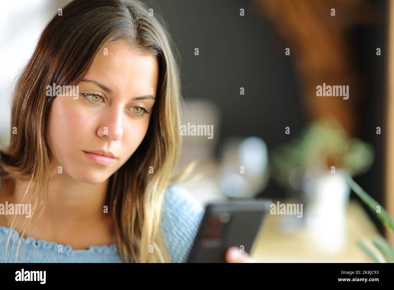 Junge Frau, die Smartphone benutzt, sitzt in einem Restaurant oder zu Hause Stockfoto