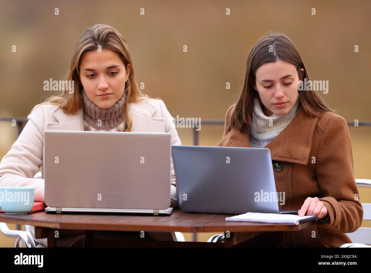 Vorderansicht von zwei Studenten, die im Winter mit Laptops studieren Stockfoto