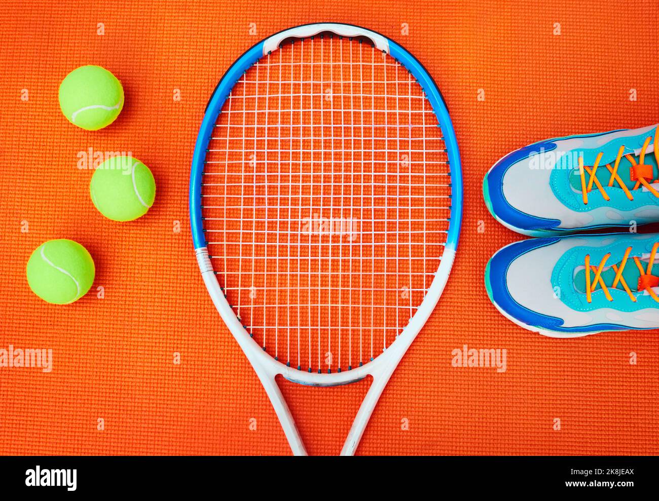 Es ist Zeit, auf das Spielfeld zu kommen. High-Angle-Aufnahme von Tennis Essentials auf einem orangefarbenen Hintergrund im Studio. Stockfoto