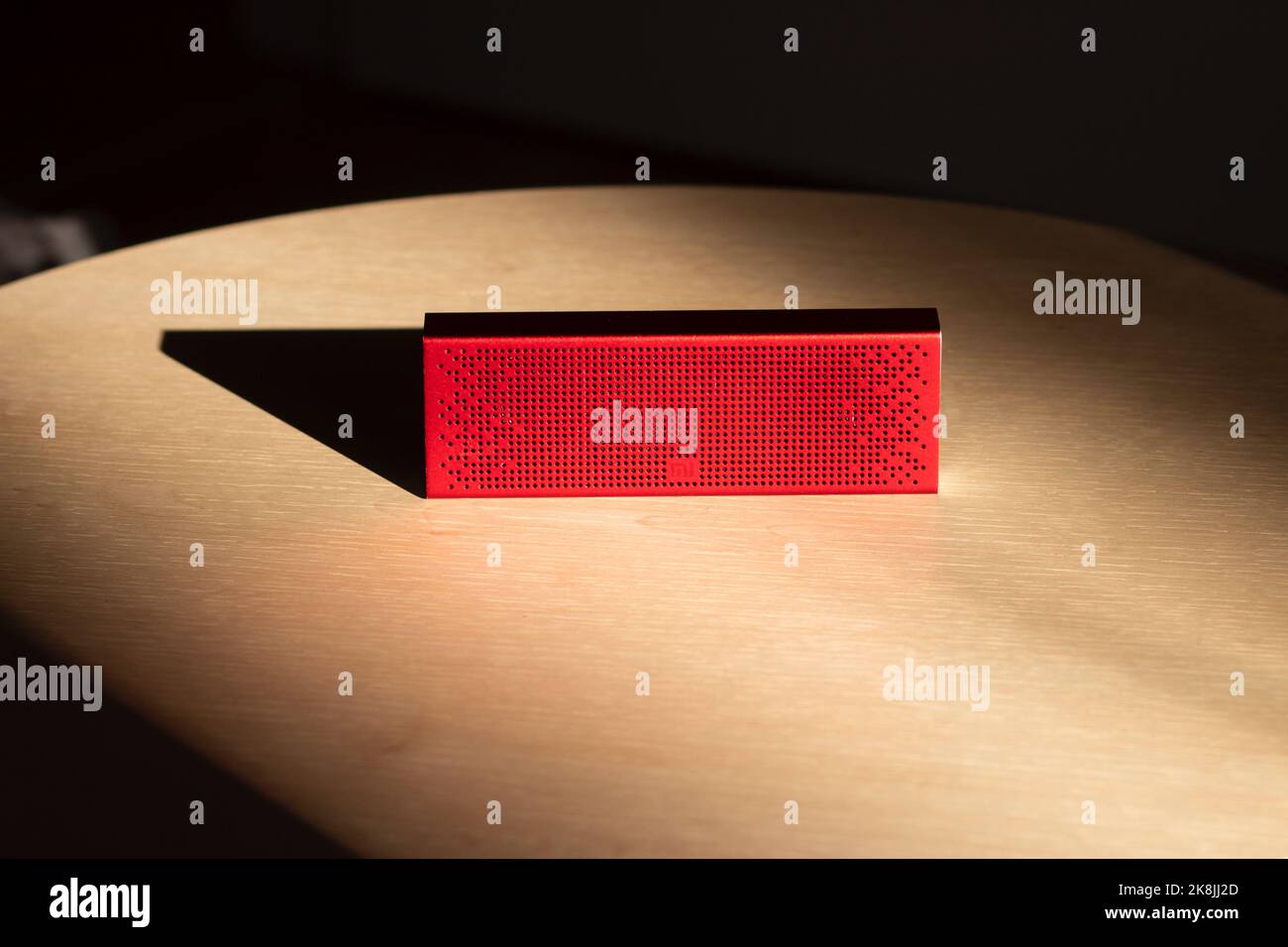 Poznan, Polen - 10.20.2022: Xiaomi Mi Bluetooth-Lautsprecher Tragbarer roter Musiklautsprecher auf einem Holztisch in den Sonnenstrahlen Stockfoto