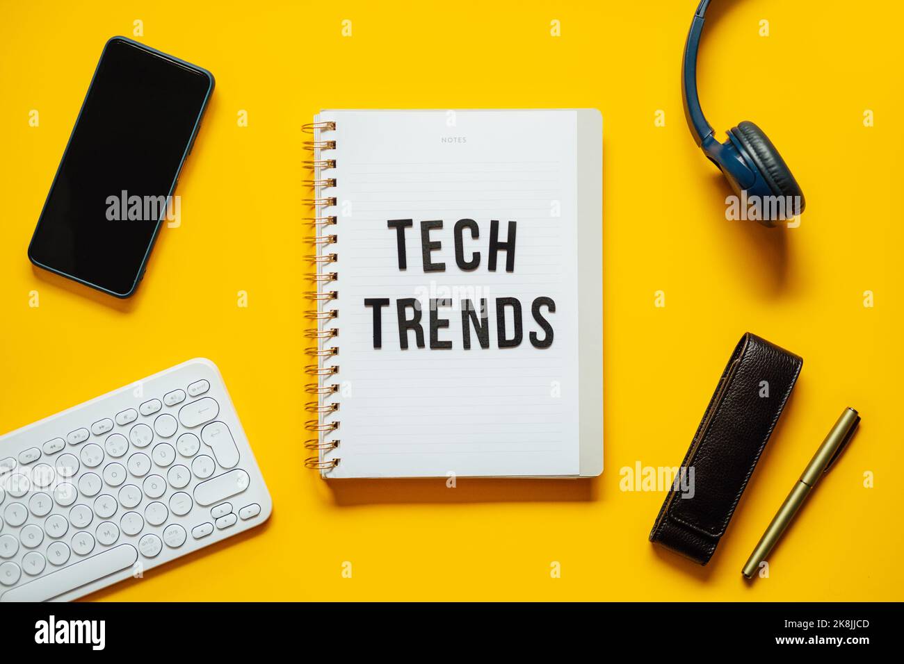 Tech-Trends, Top-Trends für neue Technologien. Worttrends auf offenem Notizblock mit verschiedenen Gadgets und Geräten auf gelbem Hintergrund. Stockfoto