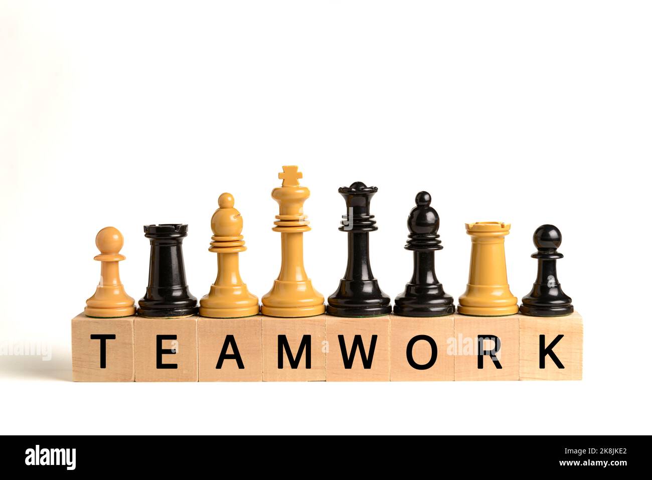 Weiße und schwarze Schachfiguren auf Holzblöcken mit dem Wort Teamwork auf weißem Hintergrund. Konzept der Teamarbeit und Zusammenarbeit. Stockfoto