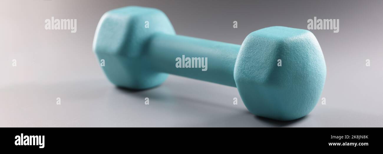 Einzelne blaue Kurzhantel auf grauem Hintergrund, Gewichtsverlust Ziel, Werkzeug für sportliche Aktivitäten Stockfoto