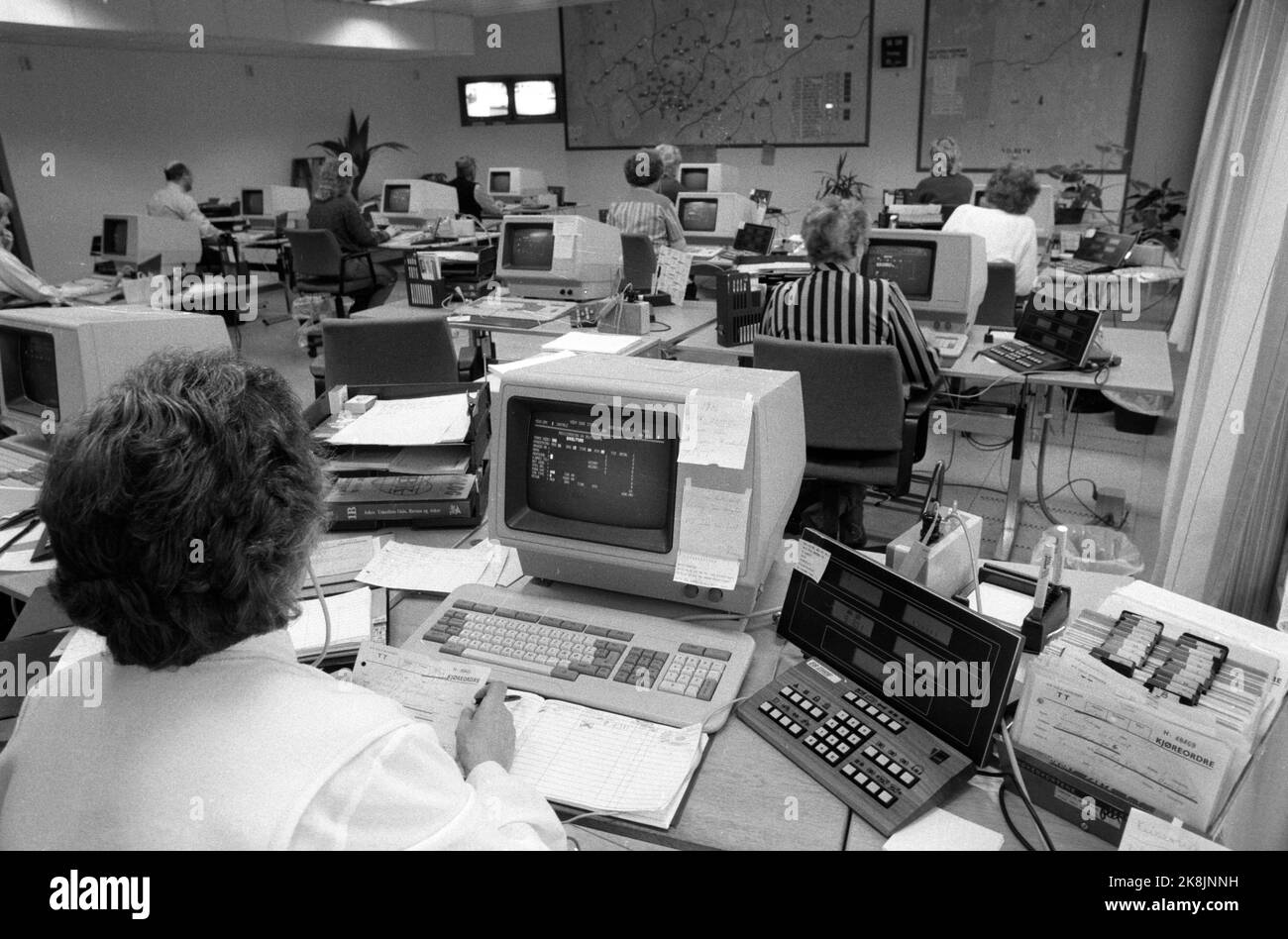 Oslo 19851115 die Einführung von Daten geht nicht so schmerzlos an allen Arbeitsplätzen. Hier, Innenräume von Oslo Taxi Central, wo nach einer Vorstandssitzung, es wurde beschlossen, die Fortsetzung seiner teuren Computer-Ausrüstung, trotz Probleme mit der Ausrüstung zu befürworten. Übersichtsbild von großen Räumen mit Männern und Frauen bei der Arbeit an Computerbildschirmen / Computern / Computern. Die Frau im Vordergrund arbeitet sowohl manuell als auch mit Daten. Sie hat rechts eine Schachtel mit handgeschriebenen Fahrbefehlen. Foto: Henrik Laurvik / NTB Stockfoto