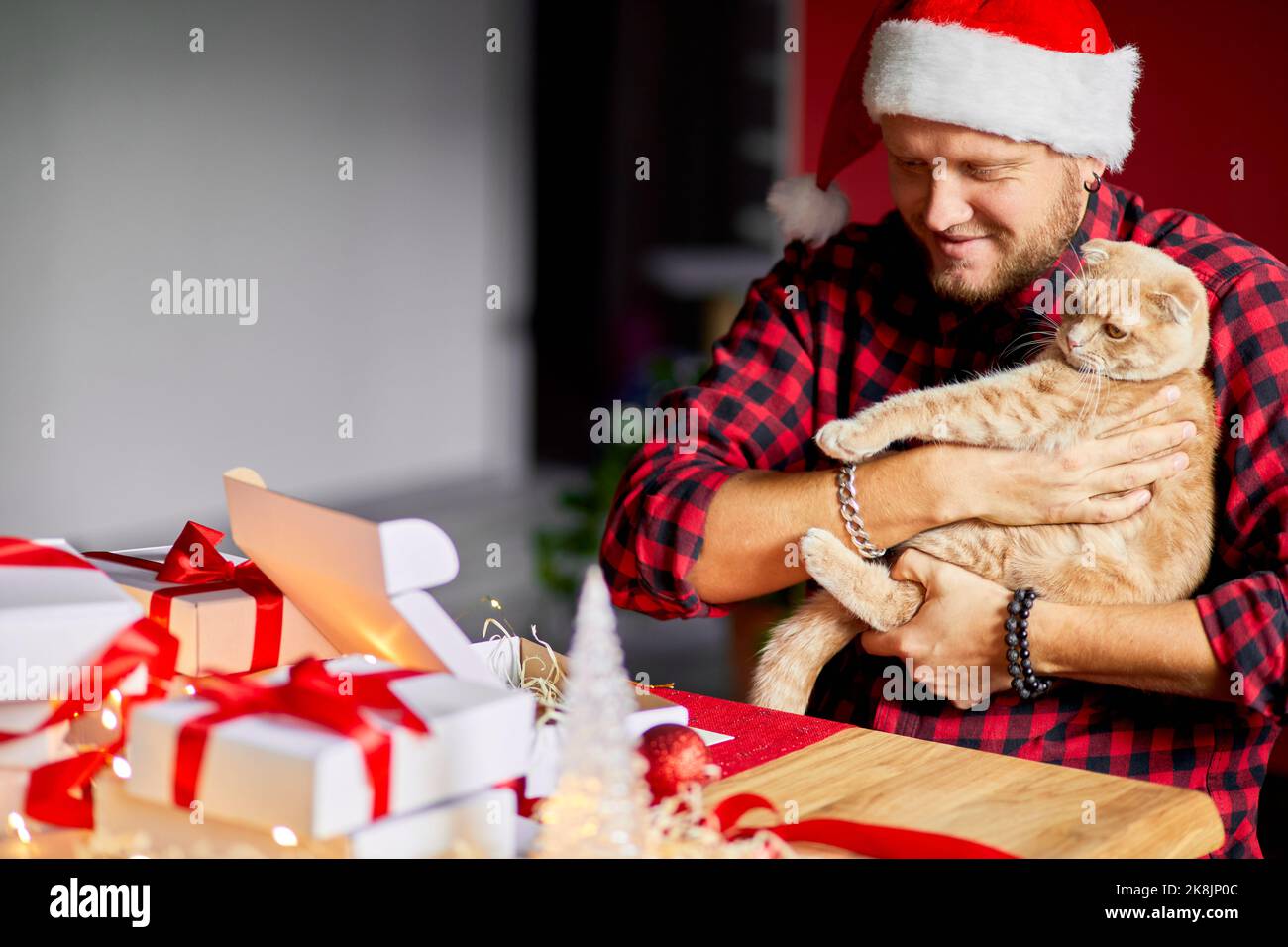 Vet man in Santa Hut und Katze in der Hand machen Grußkarte für Neujahr und Weihnachten, Gratulation für Kunden oder Freunde oder Familie, Verpackung presen Stockfoto