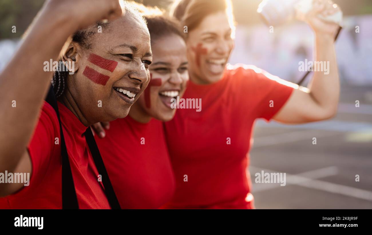 Fußballfans jubelten beim Fußballspiel im Stadion - Frauen mit gemaltem Gesicht und Megaphon ermutigen ihr Team Stockfoto