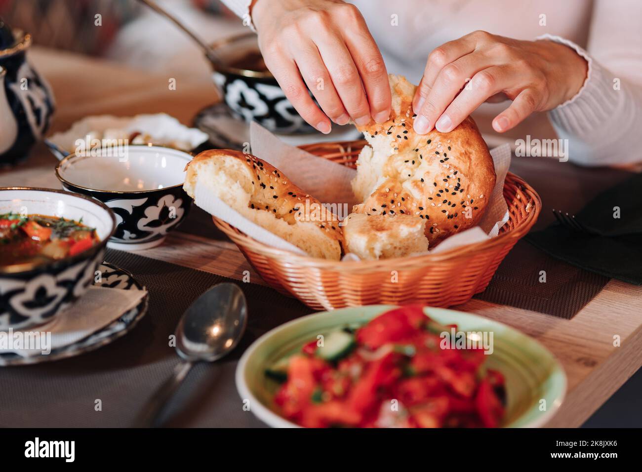 Weibliche Hände halten selbstgebackenes, natürliches frisches Brot mit einer goldenen Kruste. Traditionelles asiatisches usbekisches Brot. Stockfoto