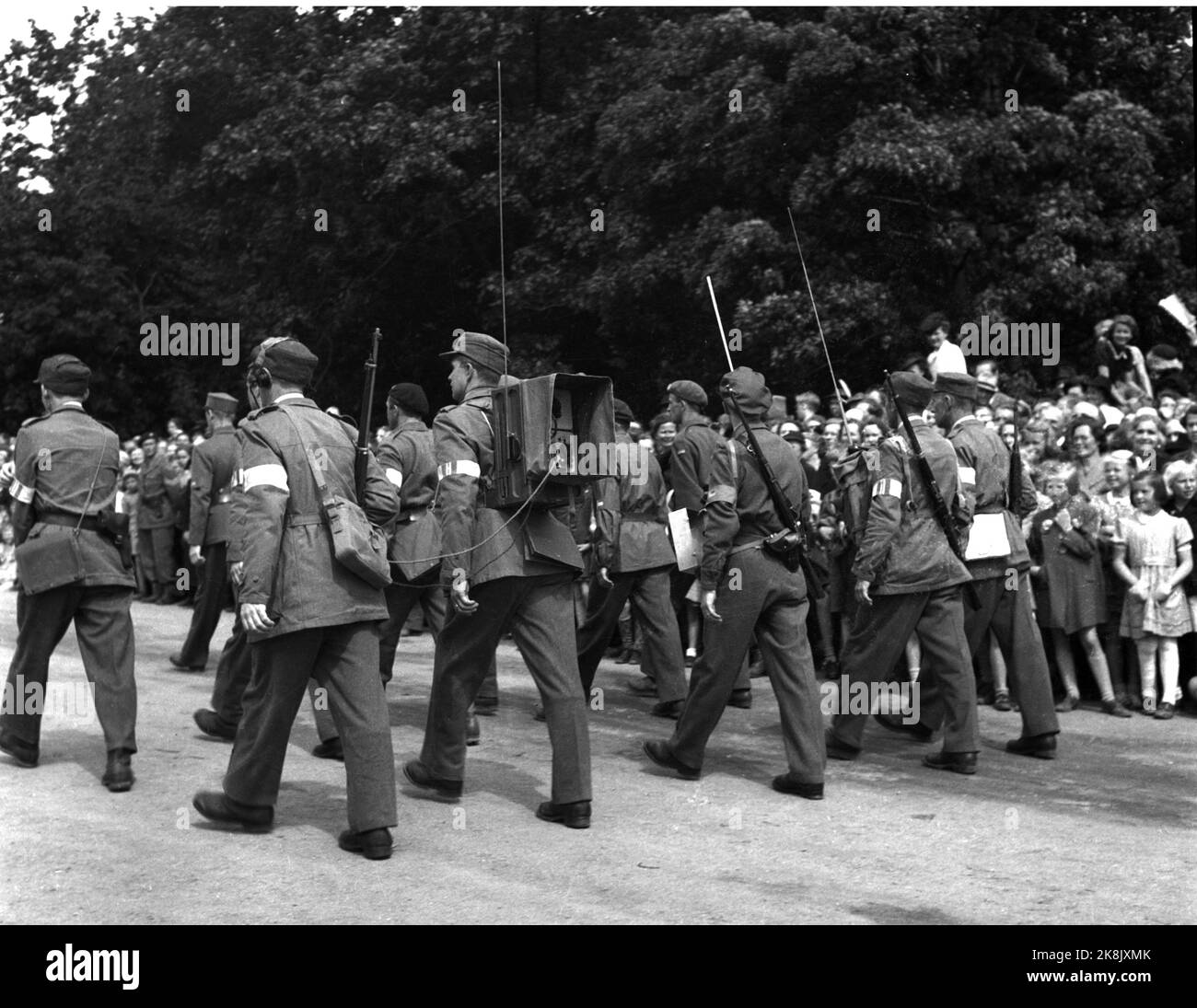 Oslo 19450609 Friedenstage 1945. Home Front Day. Die Heimatfront pariert das Karl Johans Tor zum Schloss hinauf und wird von großen Menschenmengen abgelehnt. Hier steht eine Firma Home vor Soldaten auf dem Weg zum Schloss. Soldat # 2 von v. trägt das Mobiltelefon/Verbindungsgerät in einer Box auf der Rückseite. Foto: NTB / NTB Stockfoto