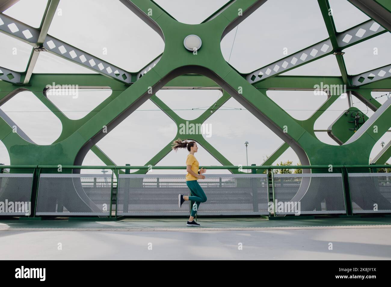 Junge Frau beim Joggen an der Stadtbrücke, gesunder Lebensstil und Sportkonzept. Stockfoto