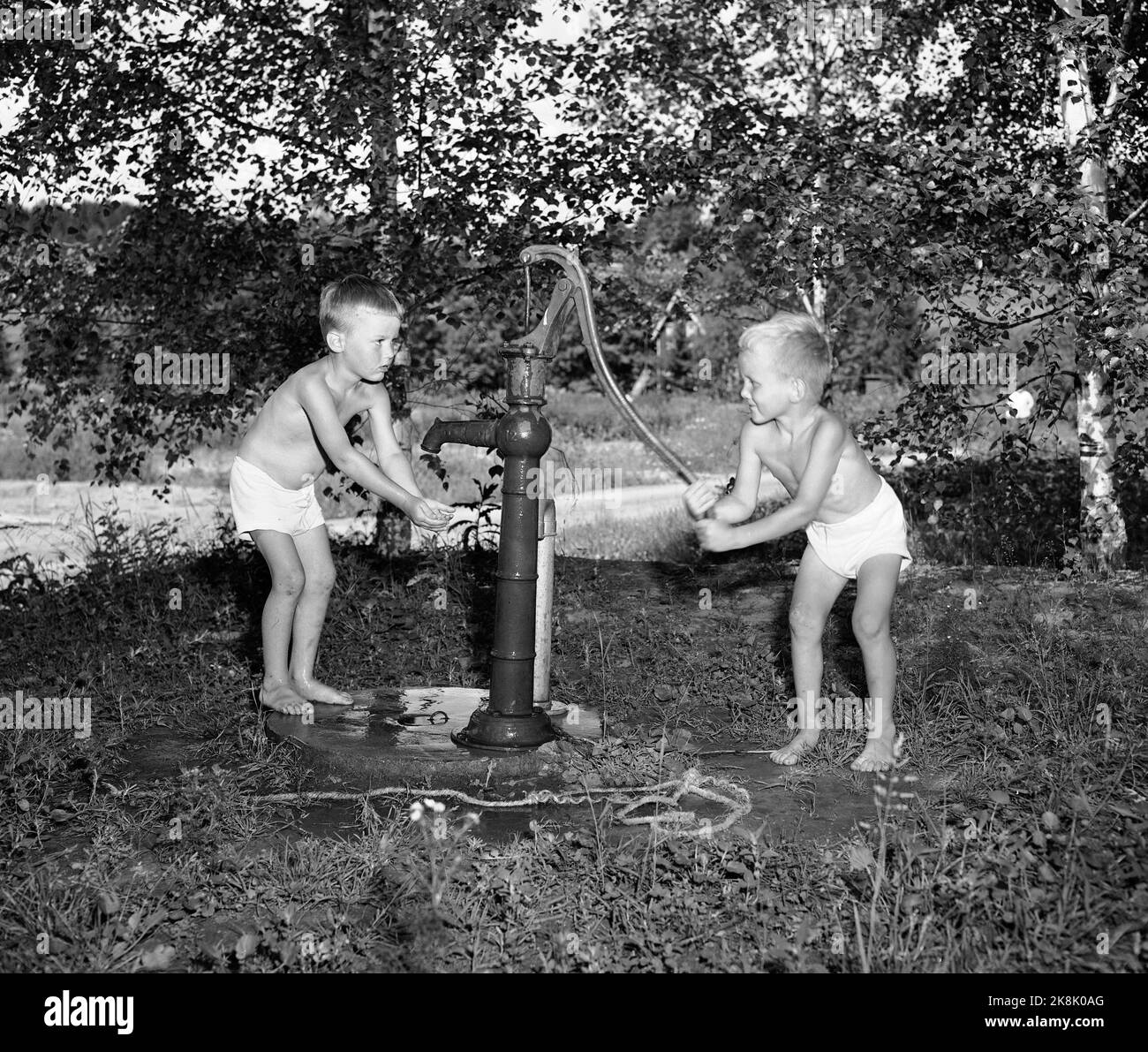 SEM, Borre, Vestfold, 19530801 Sommer auf dem Bauernhof. Zwei kleine Jungen - die vielleicht auf einem Sommerurlaub auf dem Bauernhof sein - kühlen sich mit Wasser aus der Wassersäule / Wasserpumpe ab. Foto: NTB / NTB Stockfoto