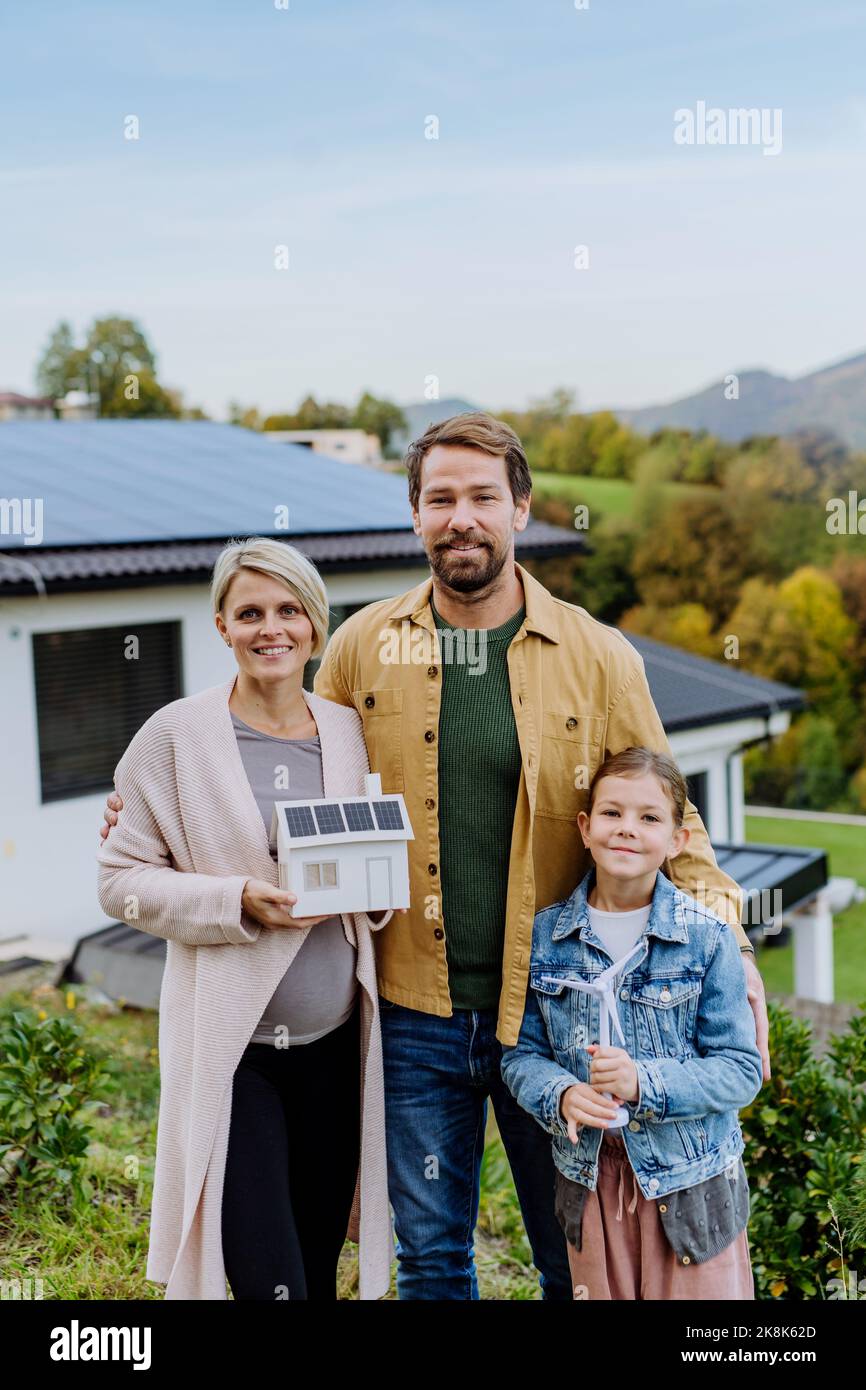 Glückliche Familie hält Papier Modell des Hauses mit Solarzellen.Alternative Energie, Ressourcen sparen und nachhaltige Lifestyle-Konzept. Stockfoto