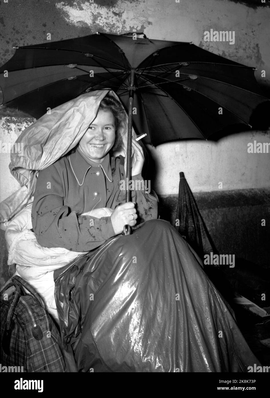 Oslo 19460713. Der Kampf, in den Urlaub zu kommen, ist schwer. Diese junge Dame vor der Ostbahn in Oslo stand im Regen an. 5 Uhr nachmittags bis zum nächsten Morgen. 10, um ein Flugticket nach Åndalsnes zu erhalten. Foto: Thorbjørn Skotaam / Current / NTB Stockfoto