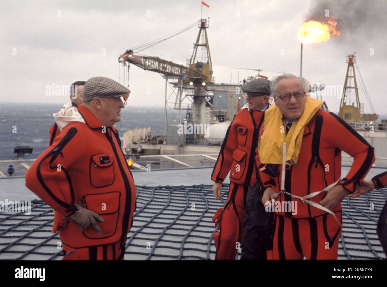 Die Nordsee 19740924 König Olav besucht das Ekofisk-Feld. Hier der König (TV) auf dem Hubschrauberdeck, in orangefarbenem Überlebensanzug und Sixpence Hut. Foto: Sven Hammerstad / NTB / NTB Stockfoto