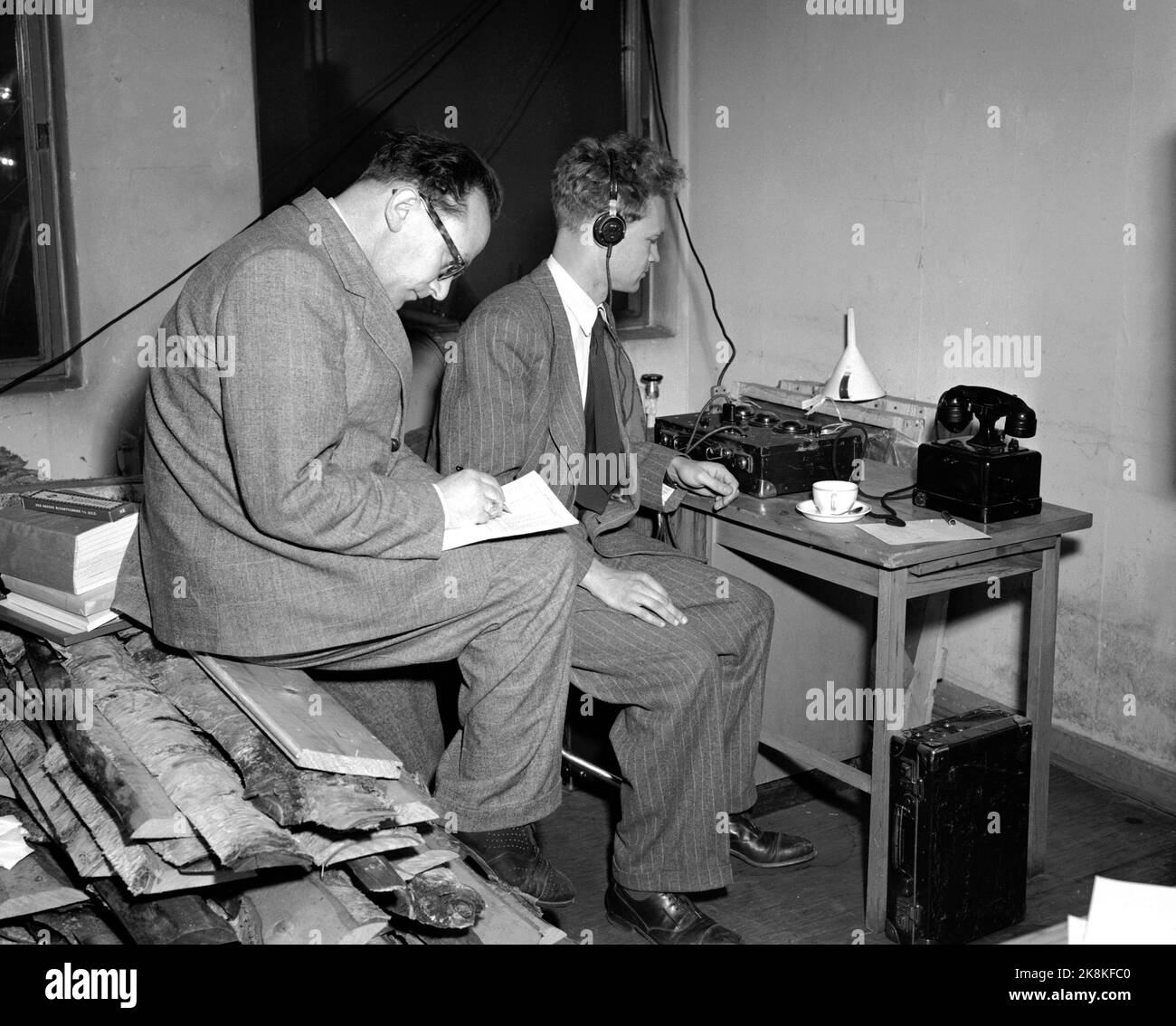 Oslo 19491010 Storting Wahlen 1949 Wahltag. Aufnahme und Sammlung von Wahlergebnissen aus dem ganzen Land. Zwei Männer arbeiten unter elenden Bedingungen, einer von ihnen sitzt auf einem Holzstapel .. Kopfhörer / Telefon Foto: NTB / NTB Stockfoto