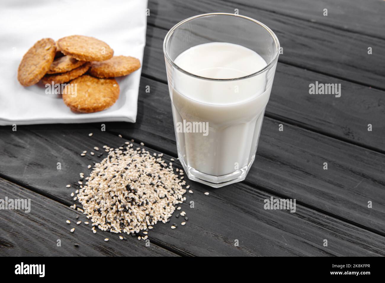 Sesammilch in einem Glas. Weiße Sesamsamen auf dem Tisch. Rohkost. Die Altrnative der Milch. Stockfoto