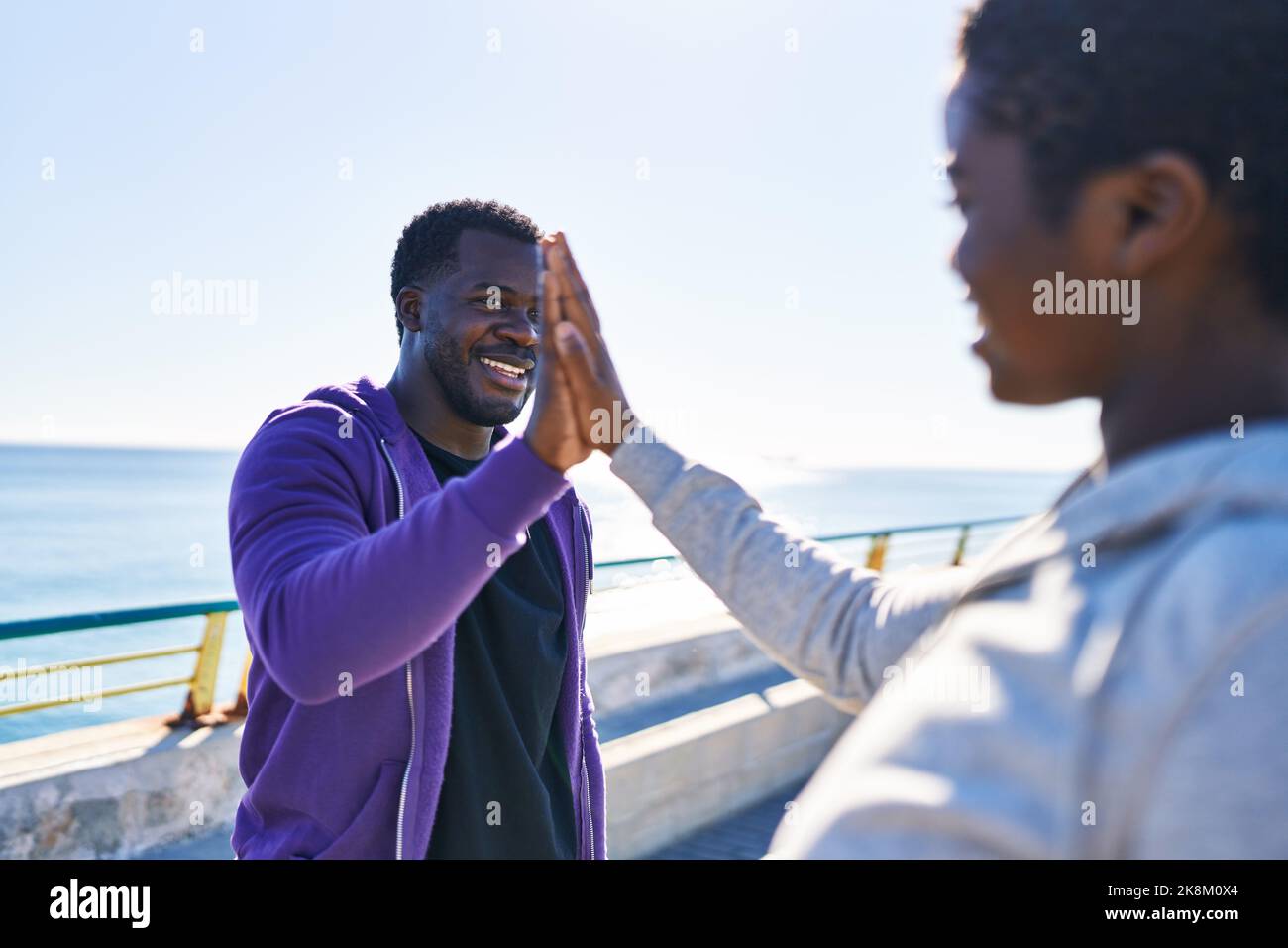 Mann und Frau tragen Sportkleidung mit hohen fünf Händen am Meer angehoben Stockfoto