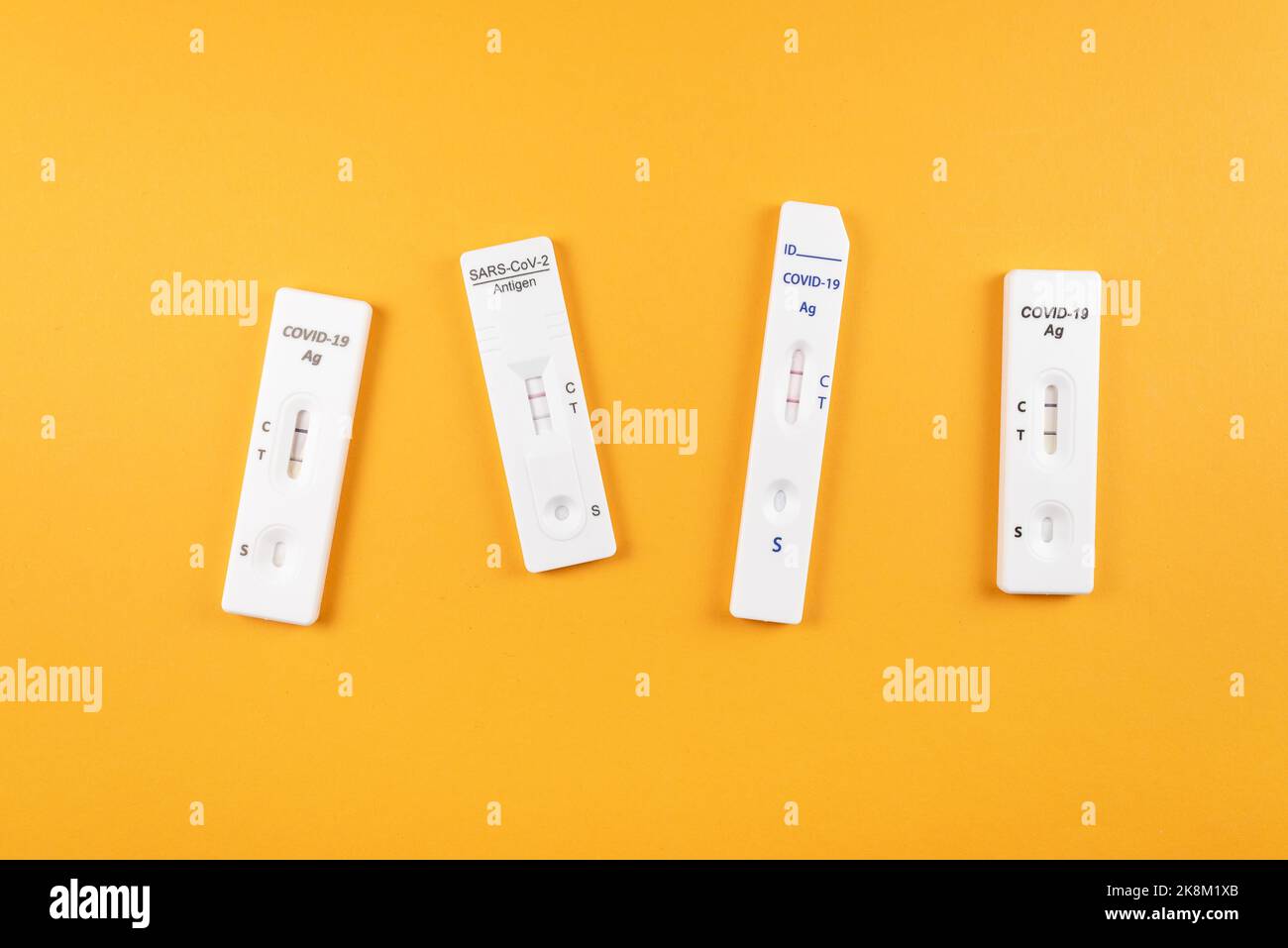 Draufsicht auf verschiedene positive Covid-19 SARS-CoV-2 Schnelltests auf leuchtend orangefarbenem Hintergrund Stockfoto