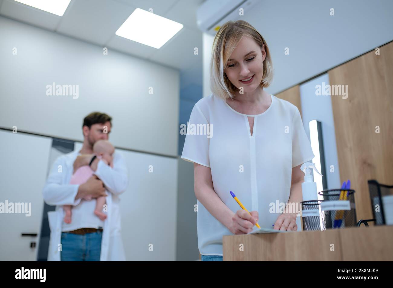 Mutter füllt vor der primären Konsultation den Papierkram für ihr Kind aus Stockfoto