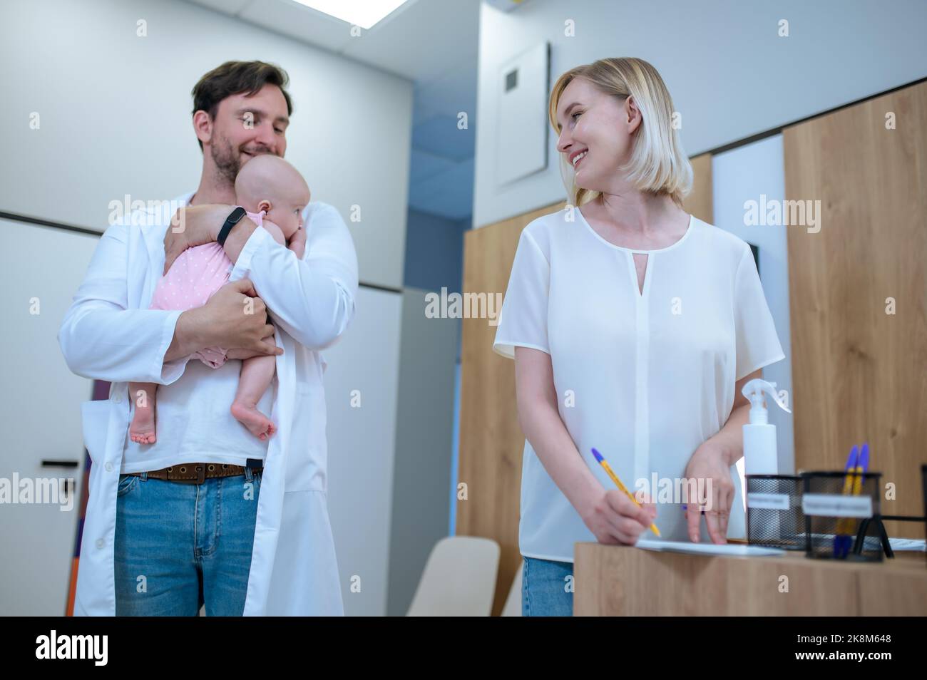 Elternteil unterzeichnet die Einwilligungserklärung für ihr Baby im Kinderarztbüro Stockfoto